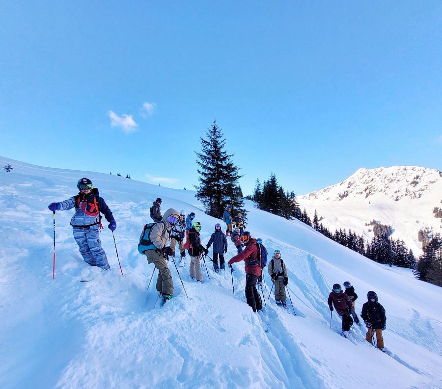 Unter blauem Himmel und der Führung erfahrener Lehrer bahnen sich die jungen Abenteurer ihren Weg durch den frischen Tiefschnee, wo jede Spur die Geschichte ihres Lernens und Erlebens schreibt